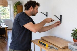 Un homme en train de fixer une étagère au mur
